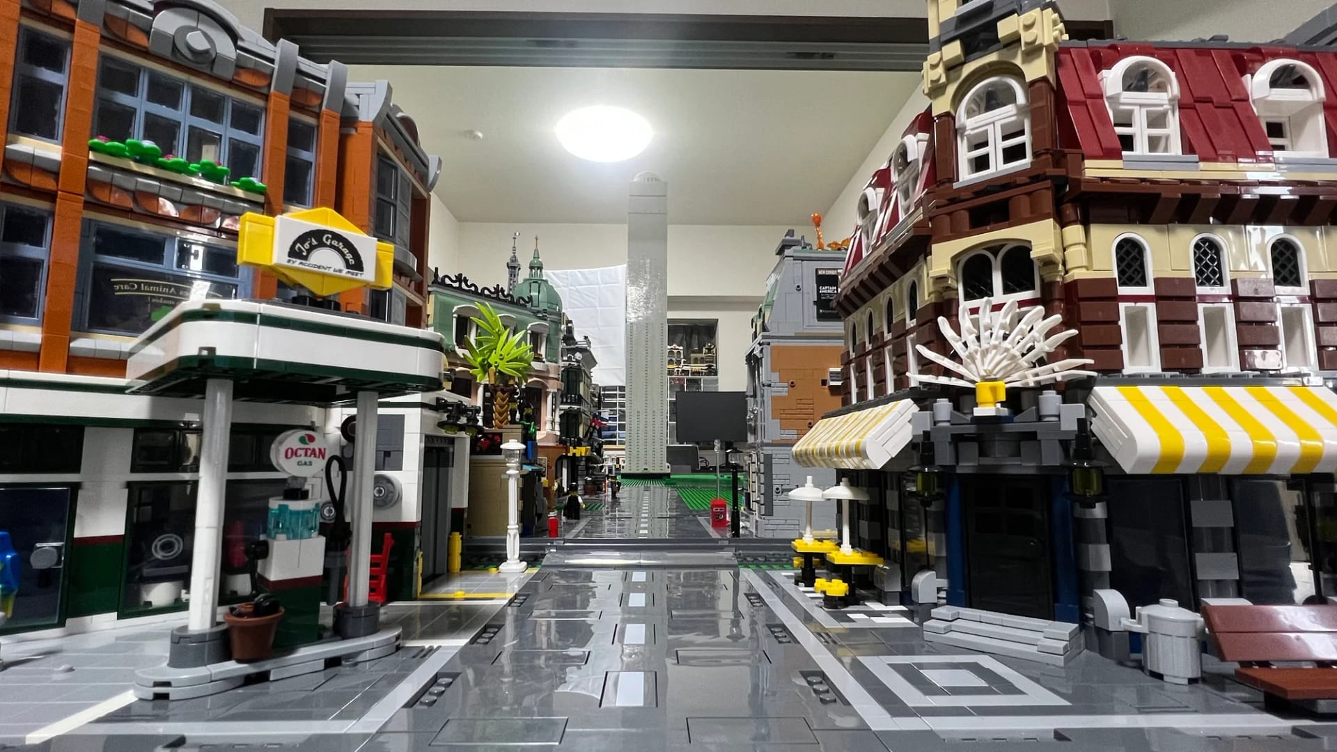 LEGOの街の道路から眺めた、ガソリンスタンドや黄色いひさしの店が並ぶ通り
