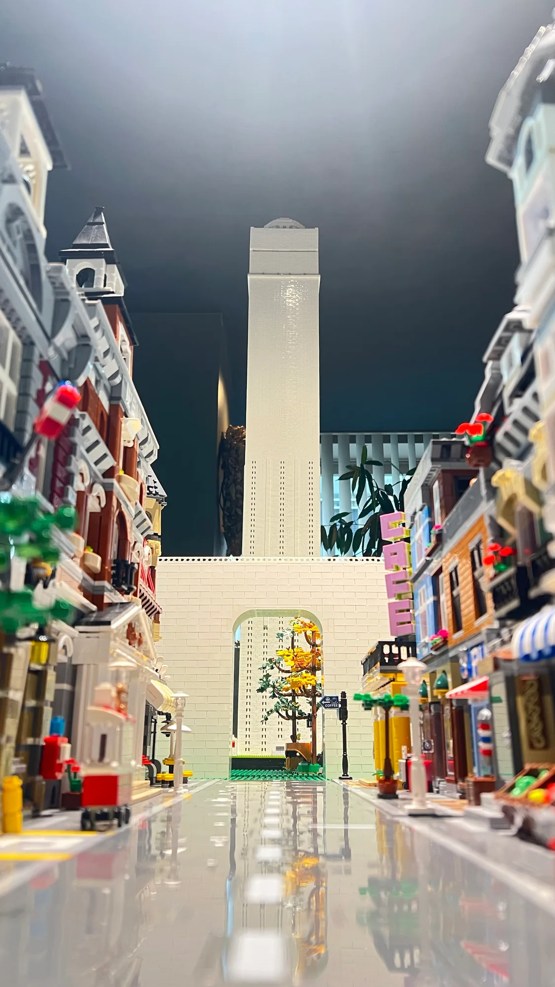LEGOの道路から見上げた白いタワーとアーチ、両側に続く色とりどりの建物