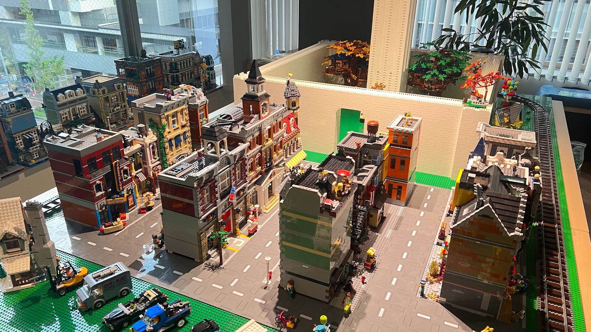 窓から光が差す工房に広がるLEGO City。建物の間を道路と線路がつなぐ制作風景