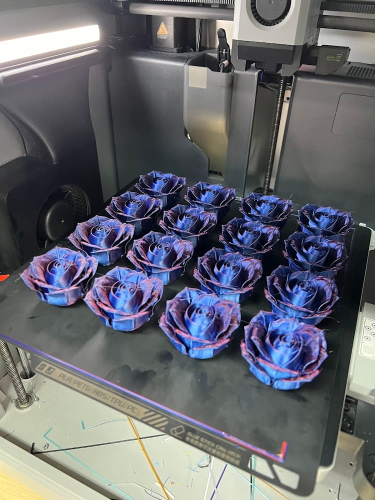 3Dプリンターの台の上に並ぶ、紫と青のバラ